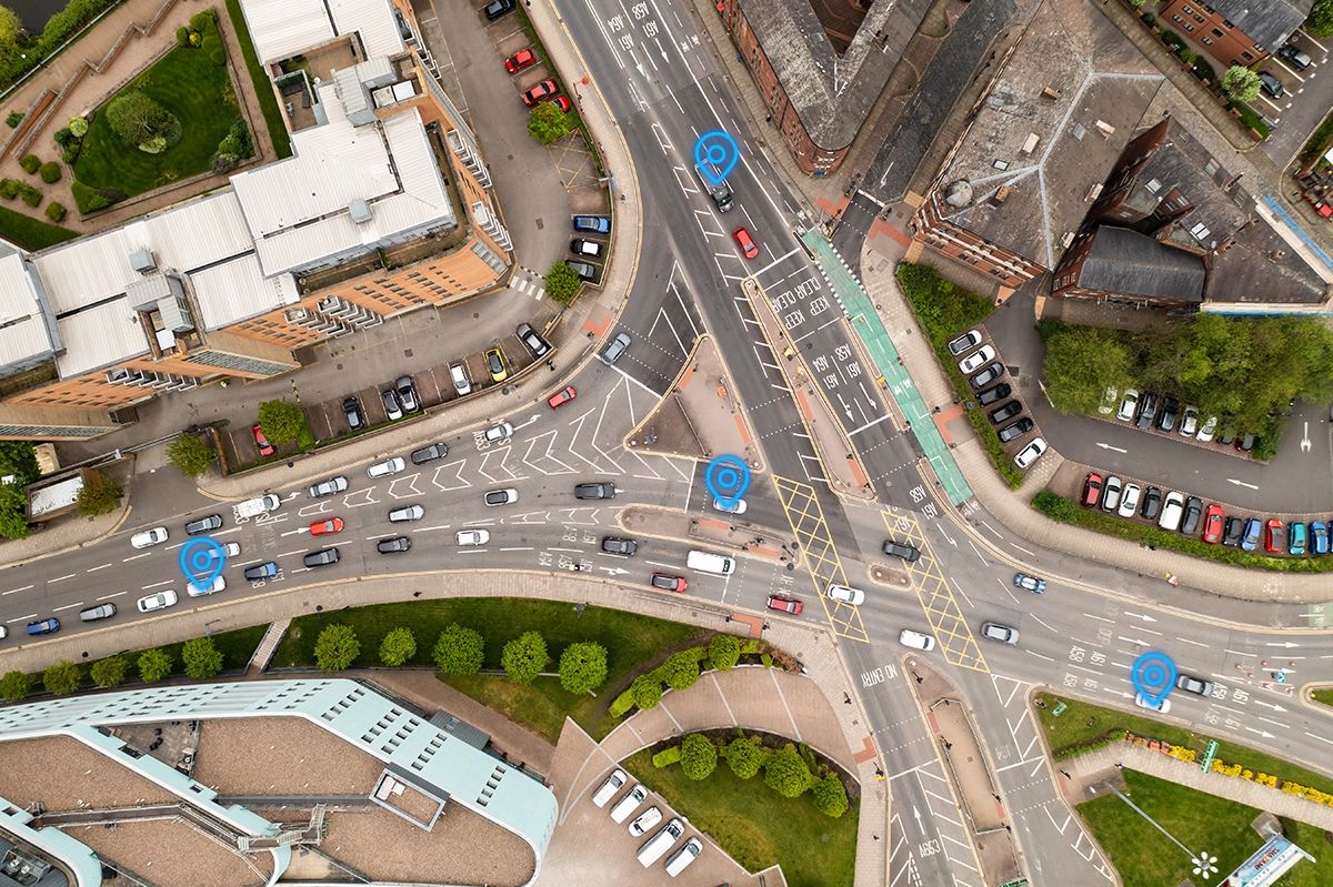 Overhead shot of busy traffic intersection in Leeds with blue pinpoint icons over some of the vehicles.