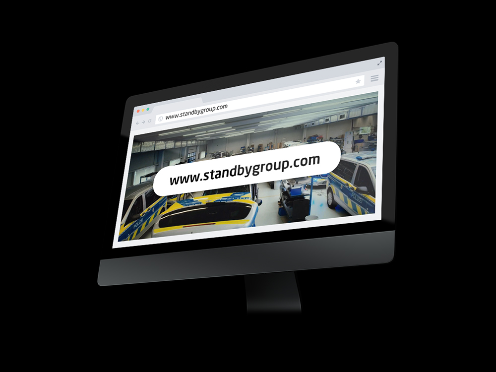 PC screen mockup at an angle on a black background showing a webpage with a big banner reading 'www.stage.standbygroup.com'.