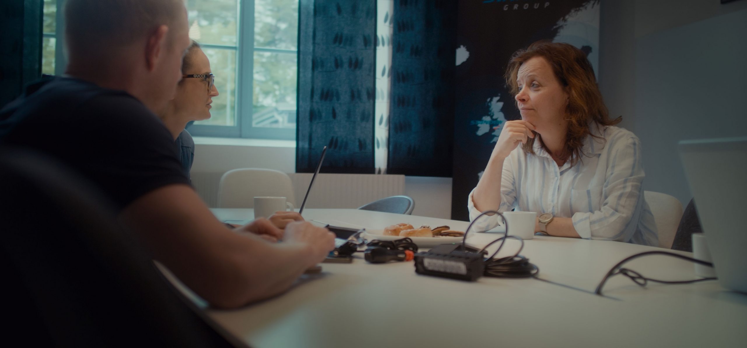 Tre personer sitter i möte i ett konferensrum.