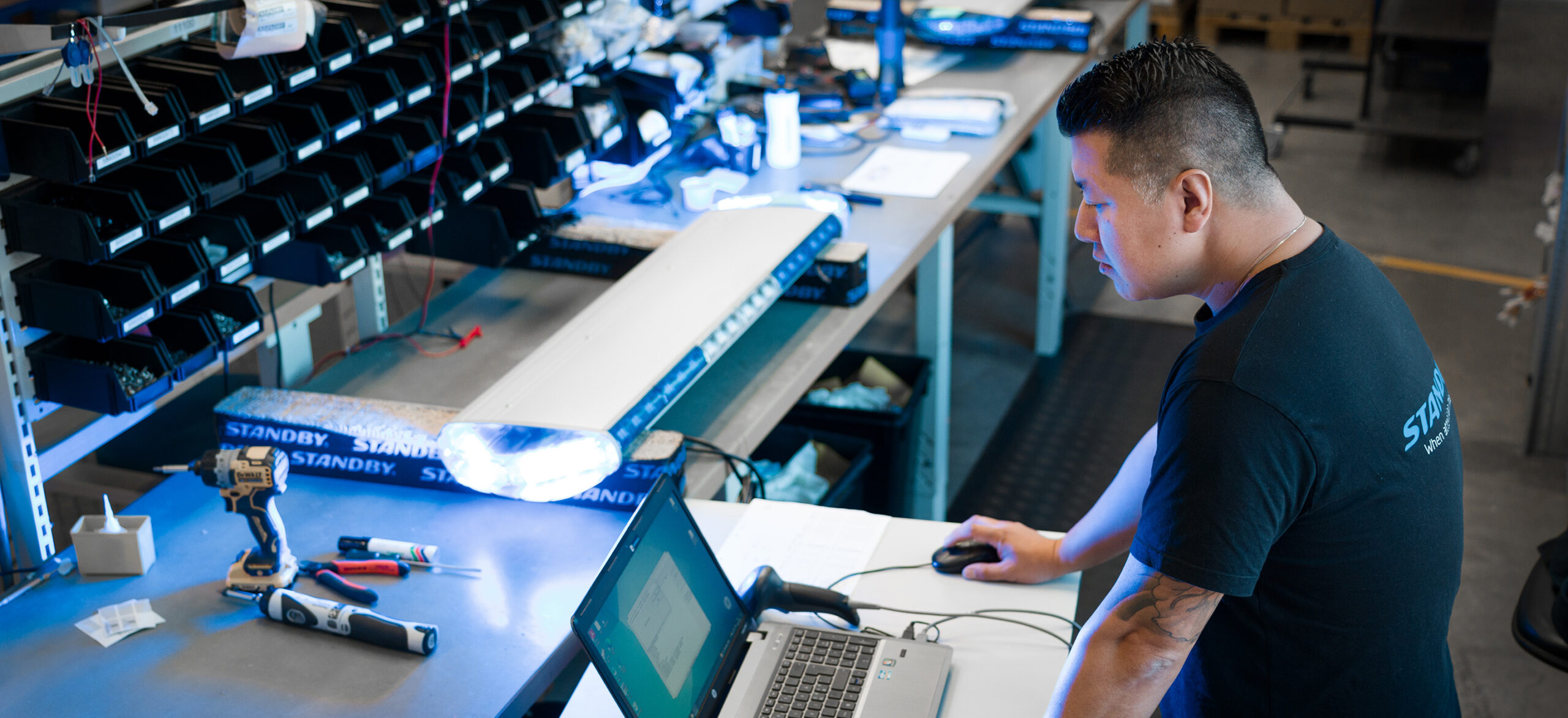 En medarbetare jobbar framför en bärbar dator bredvid en arbetsbänk med en ljusramp på.