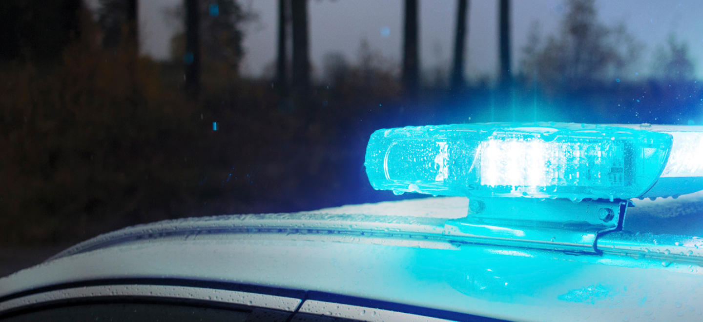 404 Hero Fallback Image Blue Lightbar Lit on top of White Vehicle in Dark Woodland Setting