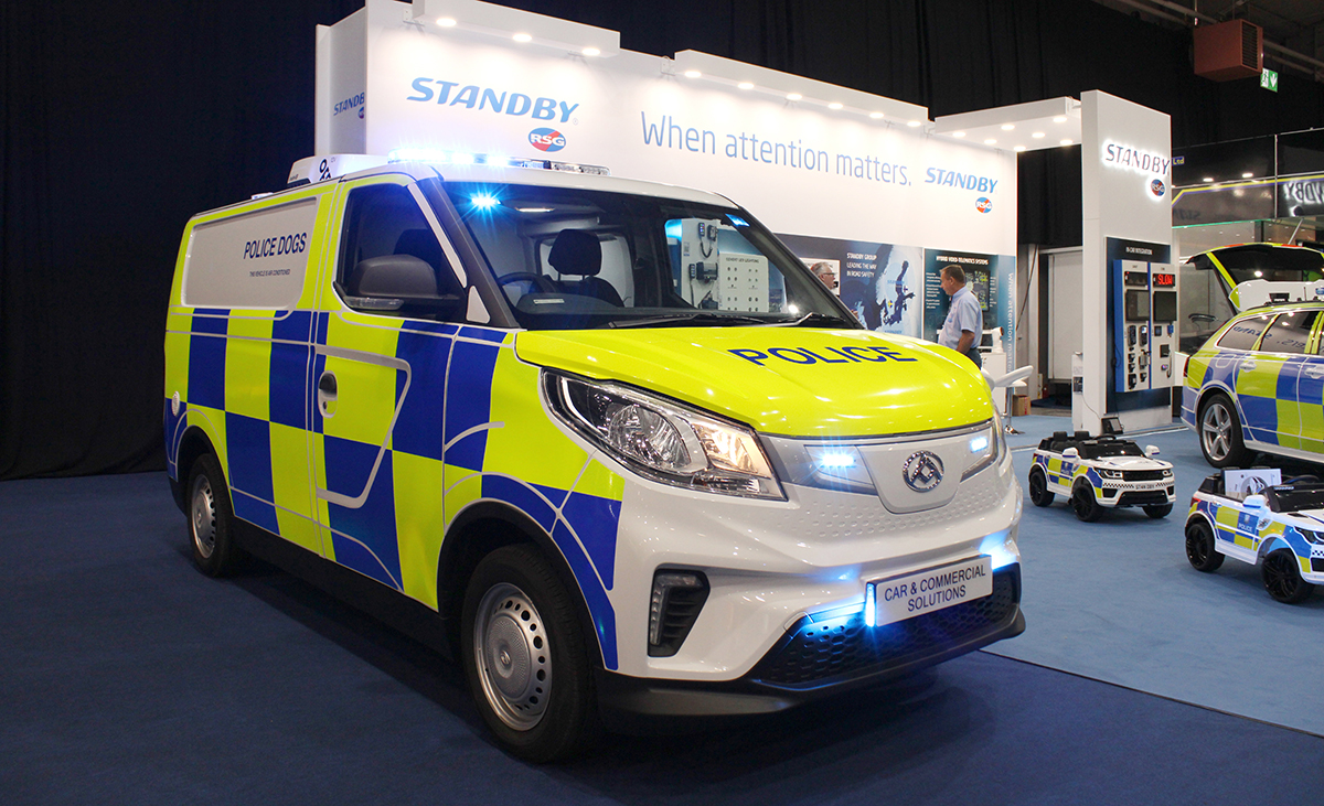NAPFM Standby Stand Police Van with 2 x children's ride-on RC cars parked next to it. The van has various lights lit blue.