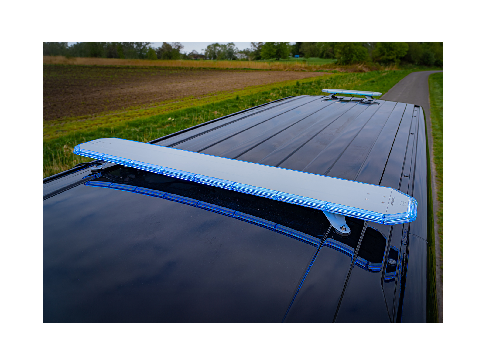 LB200 Blue - small and large models - lit angle view in situ on dark can roof against farmland/rural background with treeline.