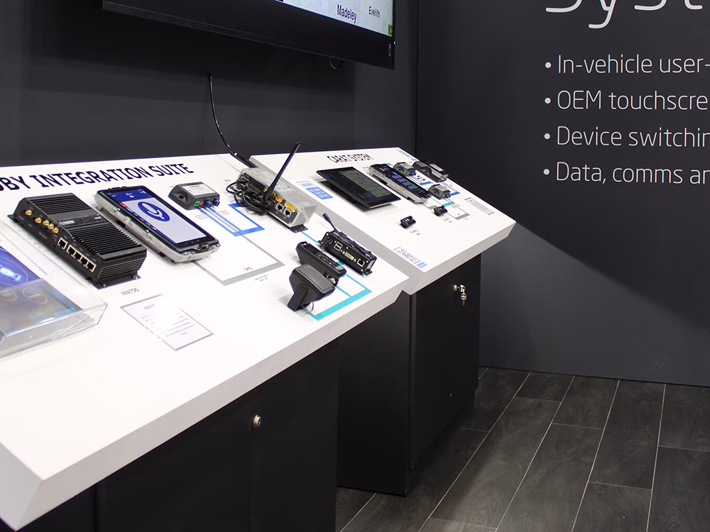 Close up view of the black zoned area on the Standby UK exhibition stand, showing floating white panels with the Standby Integration Suite and CARAT System with products,