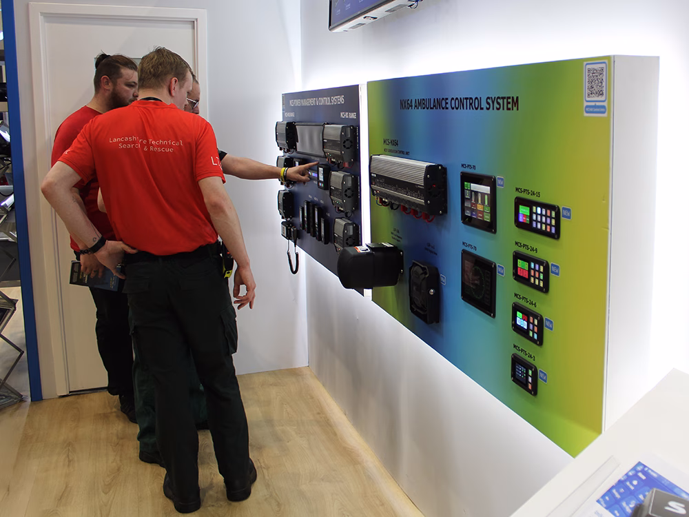 Group of workers from Lancashire Technical Search & Rescue interacting with the Power Management & Control Systems board on the Standby UK stand at the Emergency Services Show 2025