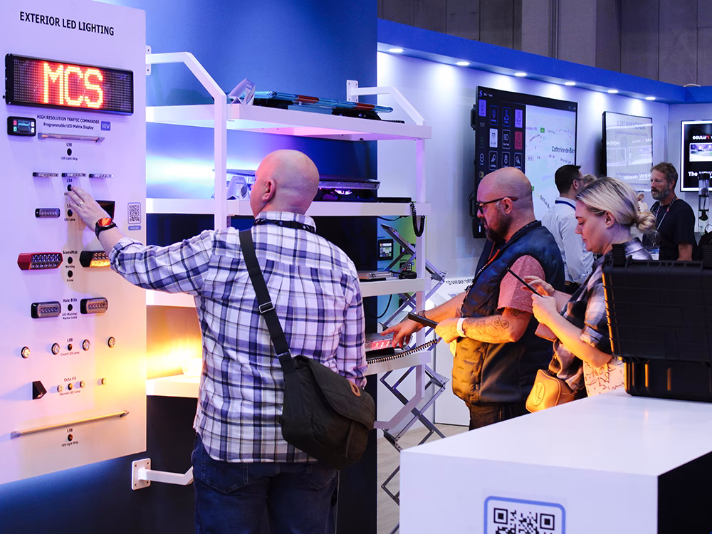 Group of stand visitors interacting with various pieces of equipment on the Standby UK stand at the Emergency Services Show 2025.