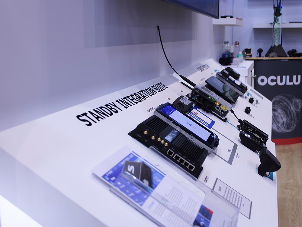 Standby Integration Suite and CARAT System panels with products on shown at an angle on the Standby UK stand the Emergency Services Show 2025. An Oculux podium in the background.