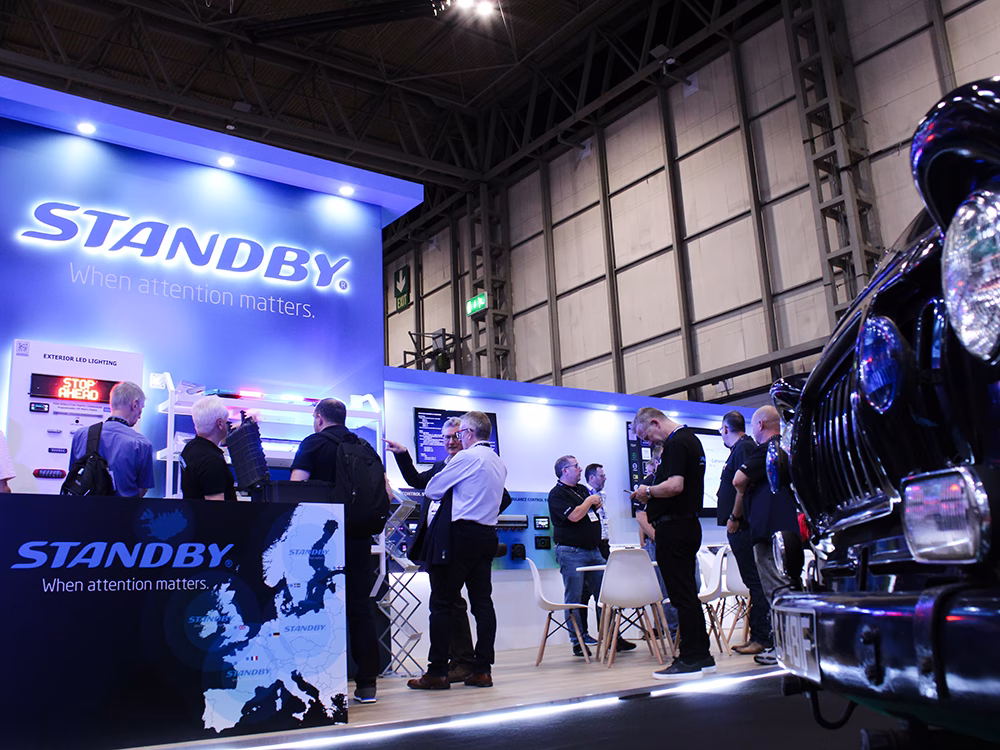 Angle view of the Standby UK stand the Emergency Services Show 2025. The front of an old black emergency vehicle is shown in the foreground.