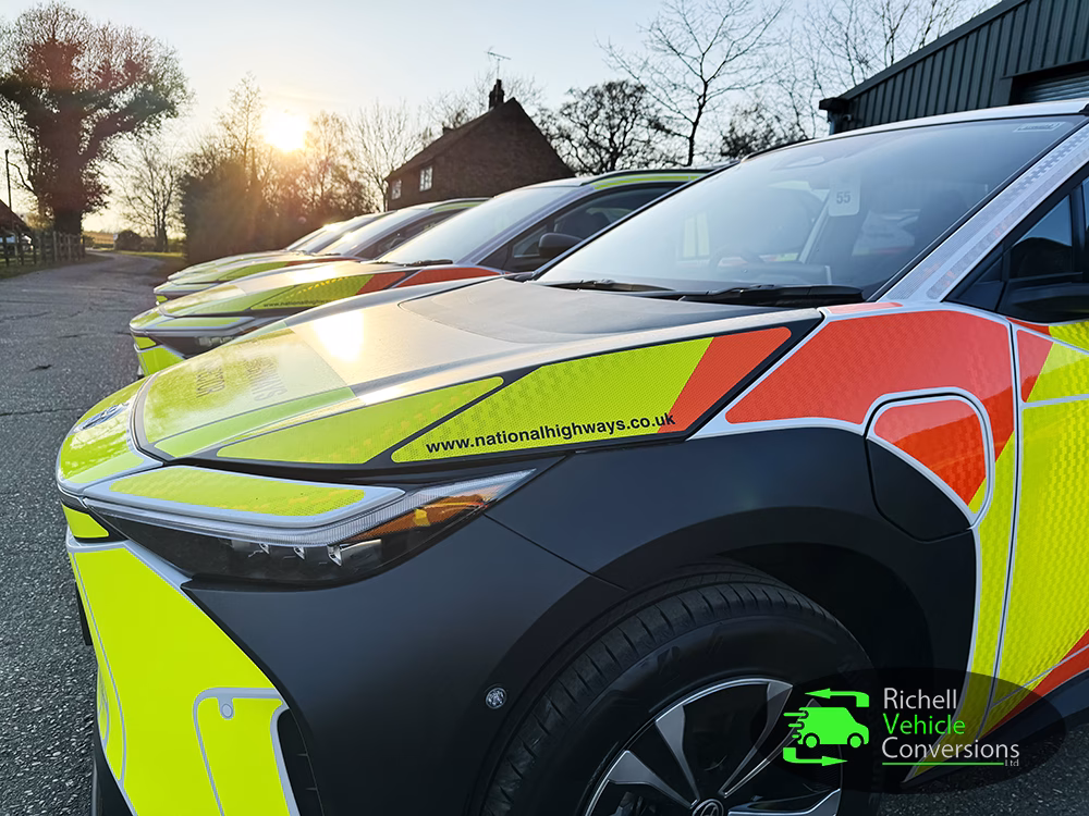 Close up of Toyota RVC BZX4s lined up at angle in front a unit. Trees and blue sky in background.