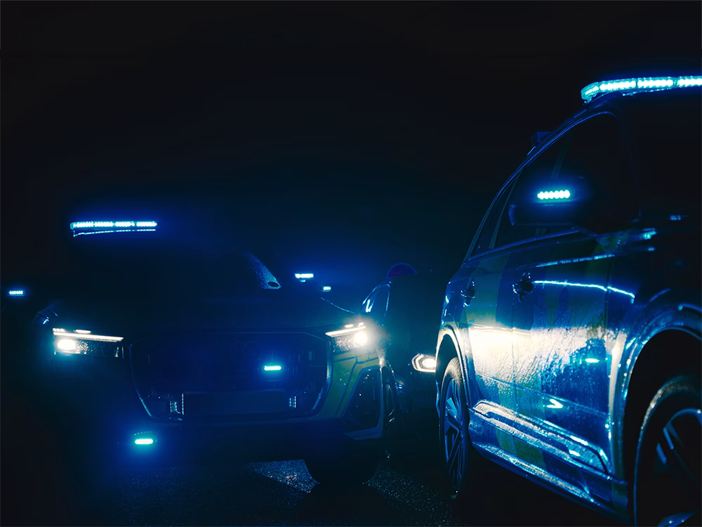 Cropped view of staggered Police cars taken at night with blue Standby warning lights.