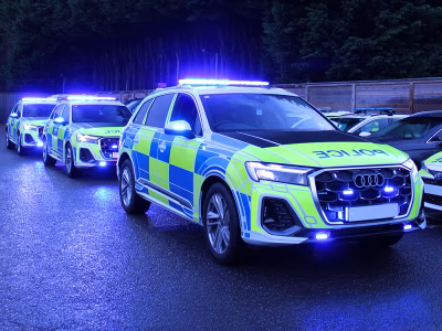 Audi Q7 Police RPU vehicles parked diagonally on a wet car park, taken at dusk. Their blue lights are activated.